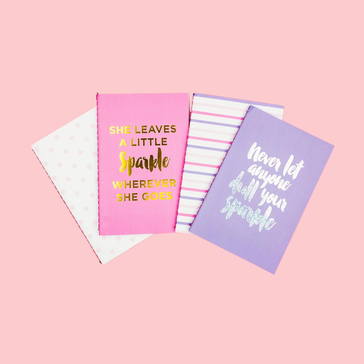 Three notebooks with motivational quotes on a pink background