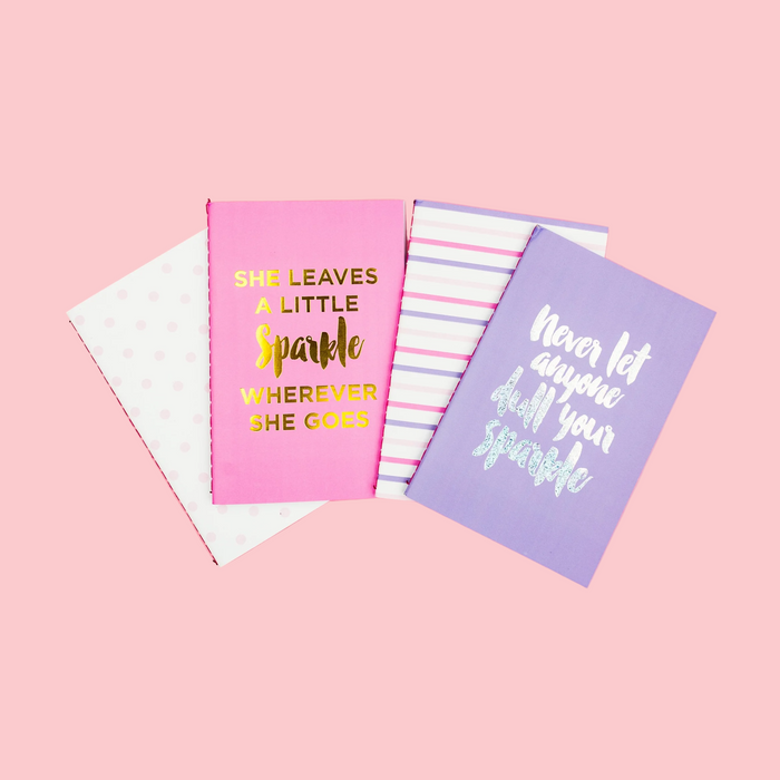 Three notebooks with motivational quotes on a pink background